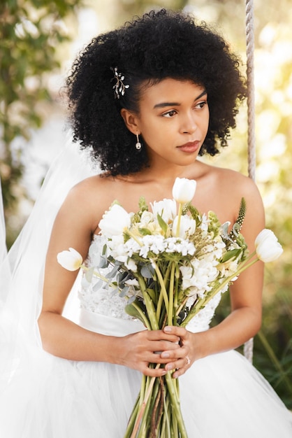 Le grand jour est enfin arrivé Photo d'une jeune mariée heureuse et belle tenant un bouquet de fleurs tout en posant à l'extérieur le jour de son mariage