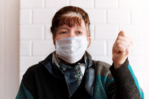 Grand-mère âgée avec un masque médical chirurgical montre un panneau d'arrêt