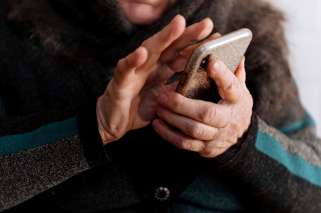 Une grand-mère âgée tient un téléphone portable pour la première fois