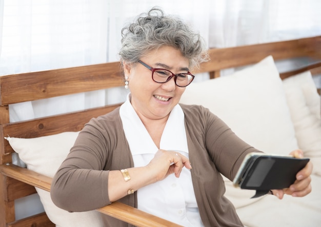 Grand-mère aînée à l'aide de téléphone faire selfie à la maison