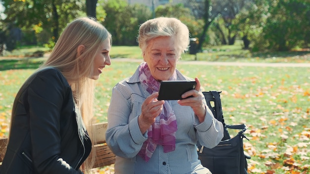 Photo grand-mère aînée montrant ses photos de petite-fille sur smartphone