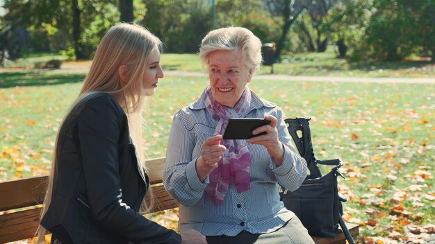 Grand-mère aînée montrant ses photos de petite-fille sur smartphone