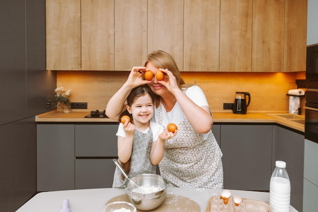 Une grand-mère attentionnée et une petite-fille s'amusent à faire des biscuits ensemble dans la cuisine de la maison Une grand-mère et une petite-fille âgées aimantes préparent un délicieux gâteau sucré