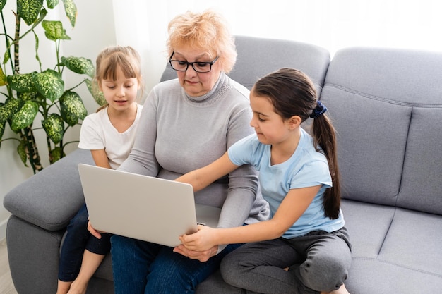 grand-mère et deux petites-filles utilisent un ordinateur portable à la maison.