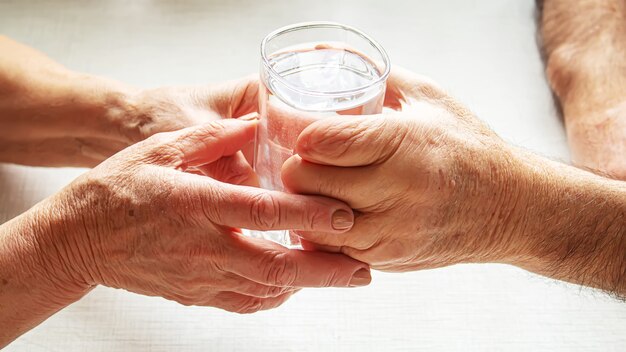 Grand-mère donne un verre d'eau à son grand-père. Mise au point sélective. nourriture.