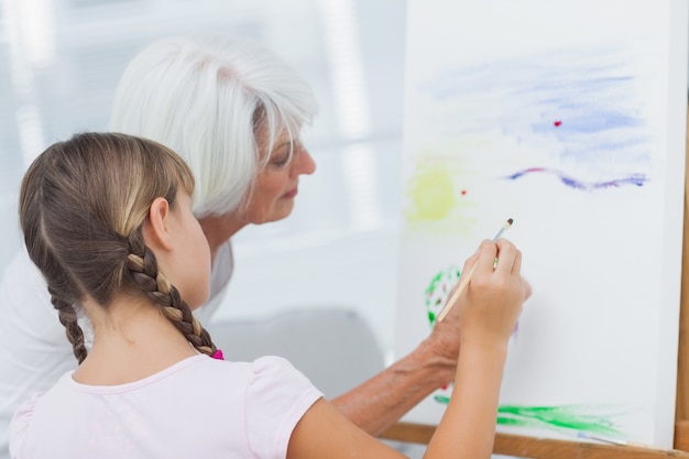 Grand-mère enseignant petite fille comment peindre