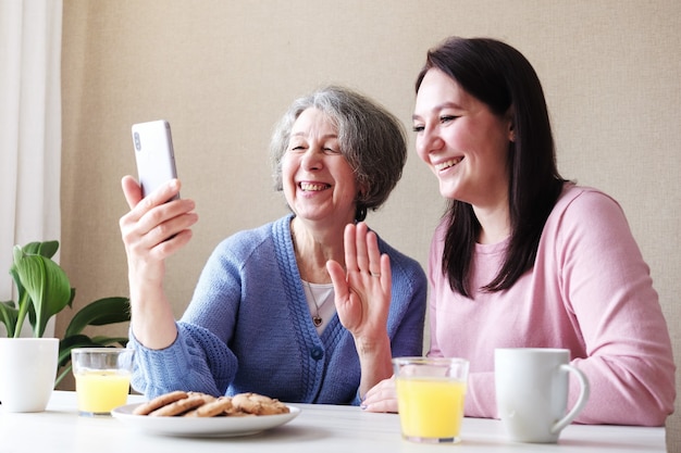 Grand-mère et fille communiquent avec des amis par appel vidéo et s'amusent
