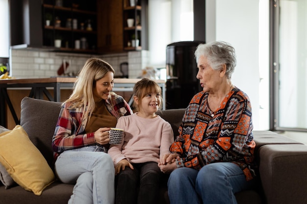 Grand-mère, fille et petite-fille partageant des histoires lors d'un après-midi chaleureux.