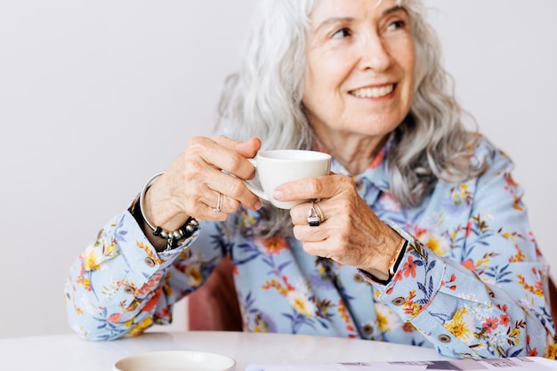 Grand-mère gaie sirotant un café dans un café