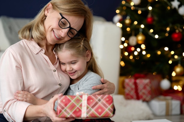 Une grand-mère heureuse donne un cadeau de Noël à sa petite-fille.