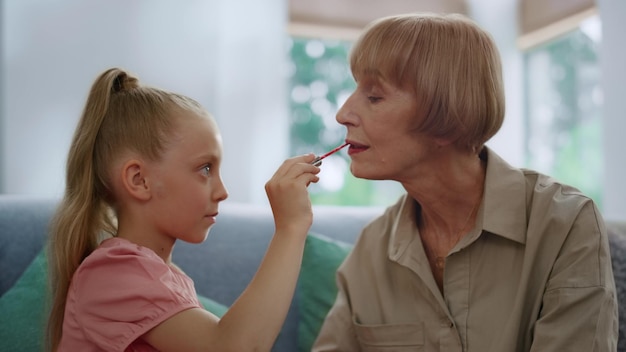 Grand-mère et jolie fille jouant avec du maquillage Famille s'amusant à l'intérieur