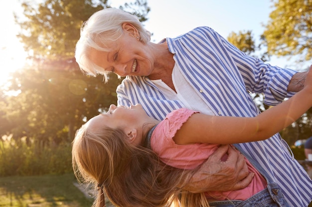 La grand-mère joue et danse avec sa petite-fille dans le parc d'été