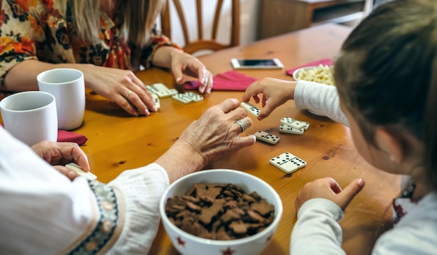 Grand-mère méconnaissable fille et petite-fille jouant au domino dans le salon