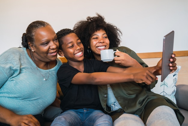 Grand-mère, mère et fils prenant un selfie avec tablette numérique.