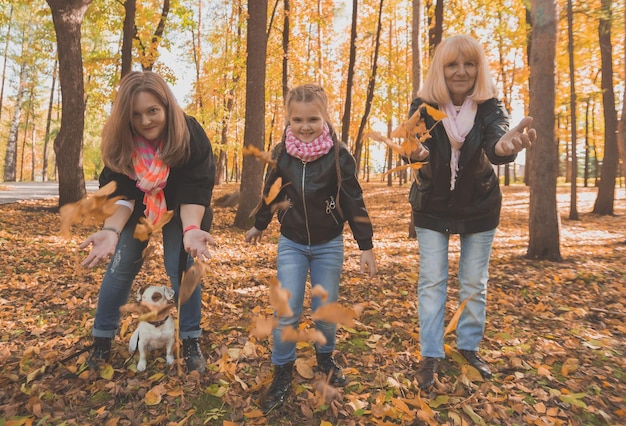 Grand-mère et mère avec sa petite-fille jettent les feuilles d'automne dans le parc d'automne et s'amusent