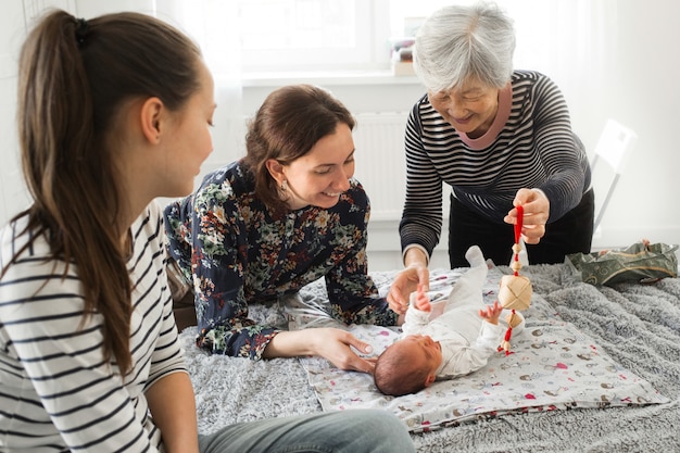 Grand-mère et mère sont des bébés heureux. Les parents jouent avec un nouveau-né