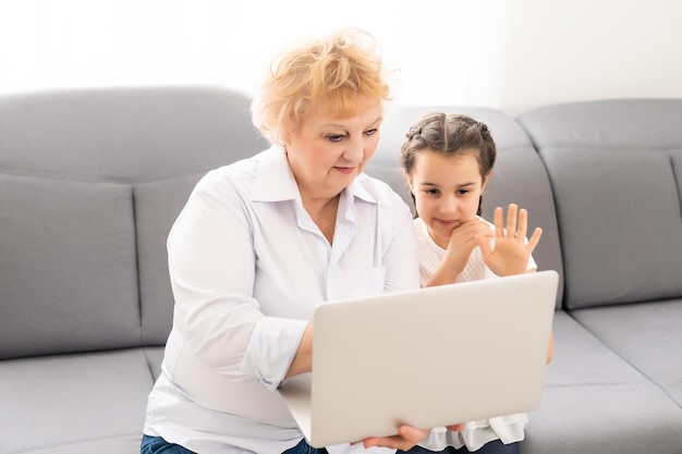 grand-mère moderne enseignant à son petit-enfant comment utiliser un ordinateur portable à la maison.