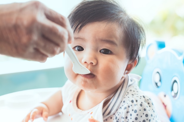 Grand-mère nourrissant mignonne petite fille asiatique avec une cuillère à la maison.