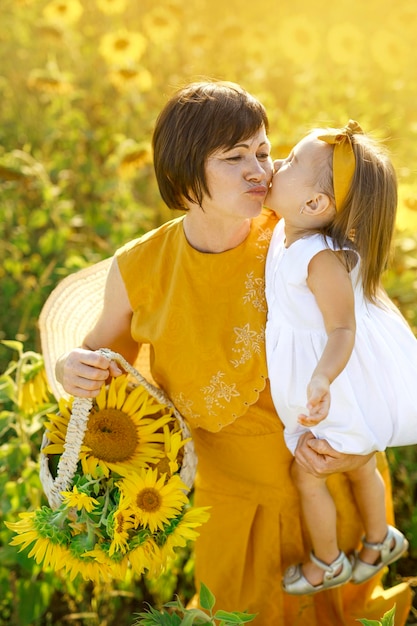 Grand-mère et petite-fille drôles avec le panier des fleurs de tournesol