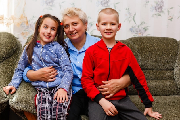 Photo grand-mère et petits-enfants assis ensemble sur un canapé dans le salon