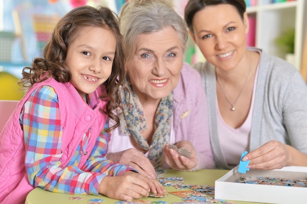 Grand-mère avec sa fille et sa petite-fille collectant un puzzle