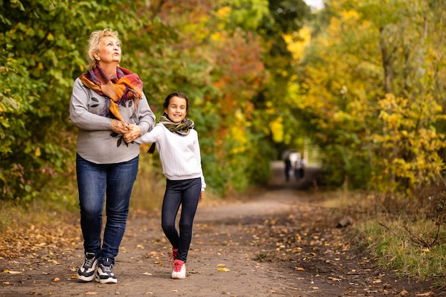 Grand-mère avec sa petite-fille pour une promenade pendant la chute des feuilles dans le parc