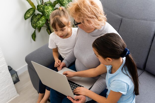 Grand-mère avec sa petite-fille utilise un ordinateur portable pour apprendre à compter ensemble à la maison.