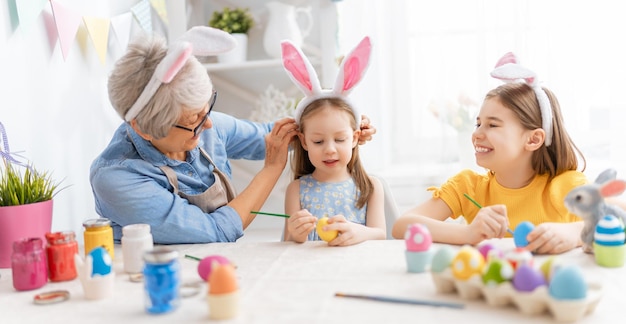 Une grand-mère et ses petites-filles peignant des oeufs Famille heureuse se préparant pour Pâques