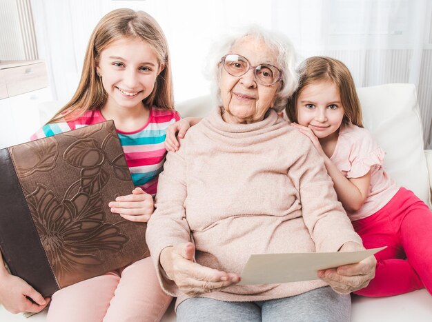 Grand-mère souriante avec ses petites-filles à la recherche de vieilles photos ensemble