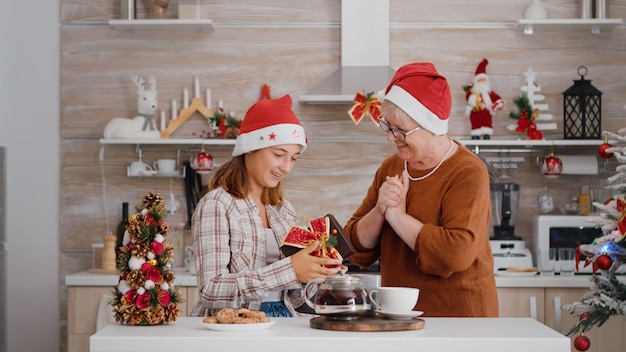 Grand-mère surprenante petite-fille avec emballage cadeau présent pendant les vacances d'hiver traditionnelles