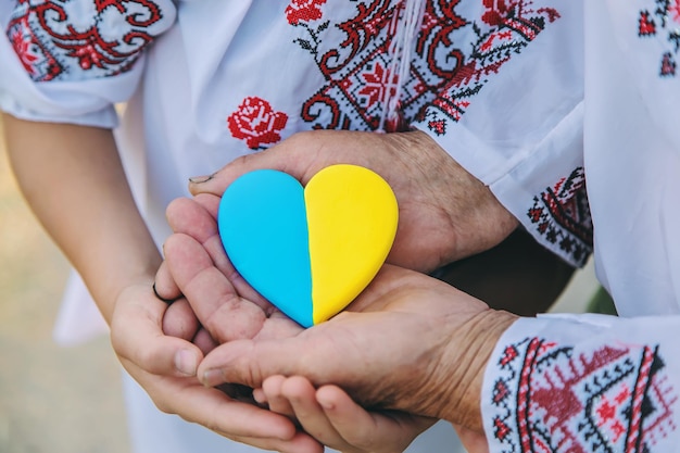 Grand-mère tient dans ses mains un cœur de la couleur du drapeau ukrainien Mise au point sélective