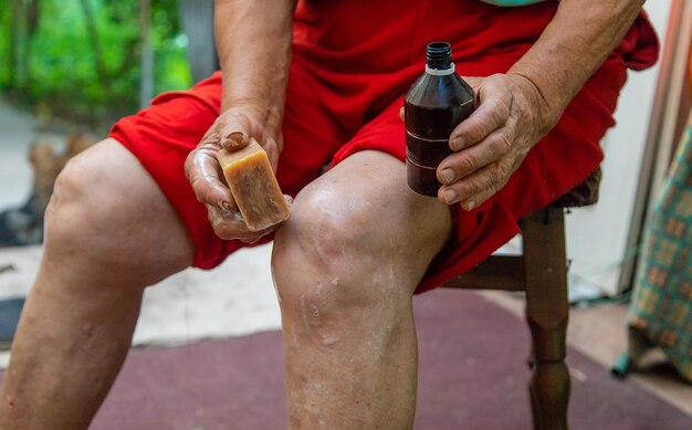 Photo grand-mère traite ses genoux avec du savon mise au point sélective