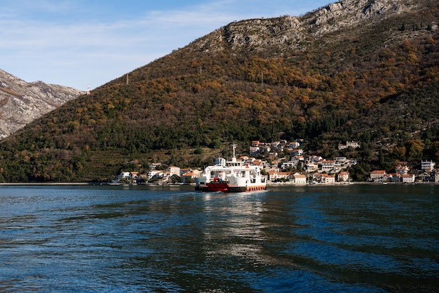 Un grand navire navigue vers une ville sur la côte de la mer au pied des montagnes