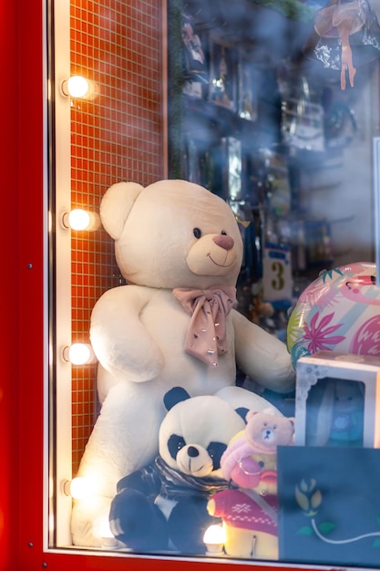 Un grand ours en peluche blanc et d'autres jouets dans la vitrine