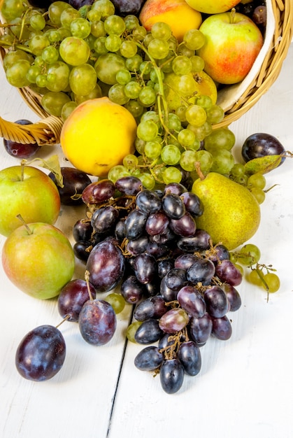 grand panier avec des fruits d'automne sur une table en bois blanc