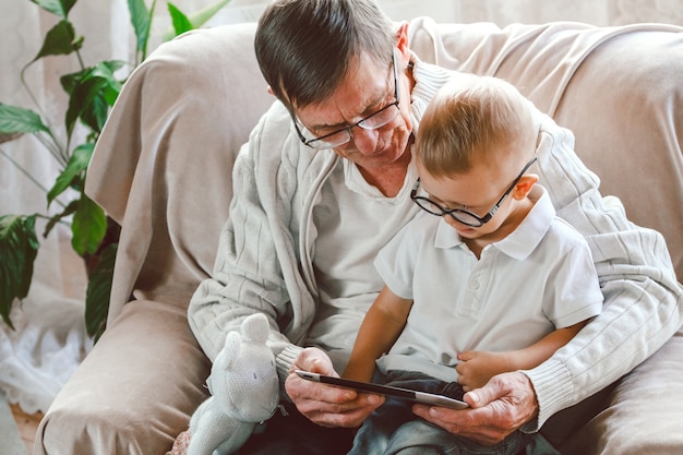 Grand-père âgé et petit-fils lisant un livre ensemble