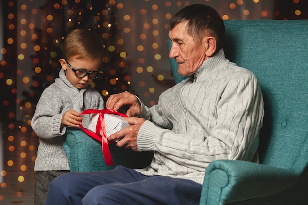 Photo grand-père âgé et son petit-fils donnent et ouvrent un cadeau de noël