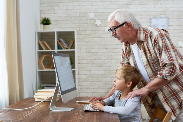 Grand-père apprenant à un petit garçon à utiliser Internet