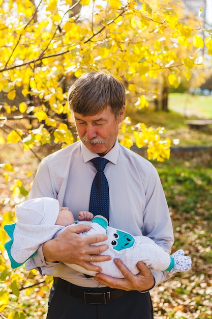 Grand-père avec bébé, un petit garçon se promène à l'automne dans le parc ou la forêt. Feuilles jaunes, la beauté de la nature. Communication entre un enfant et un parent.