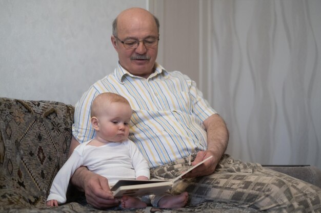 Grand-père caucasien et petite fille lisant la réservation assis ensemble dans la chambre