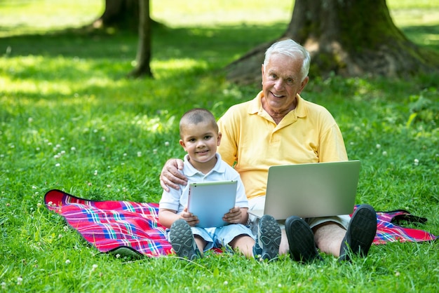 grand-père et enfant à l'aide d'un ordinateur tablette dans le parc