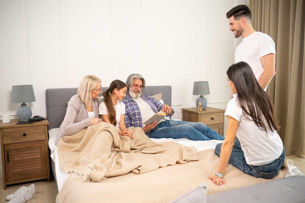 grand père de famille multigénérationnel mère et grands-parents seniors lisant un livre avec sa petite-fille