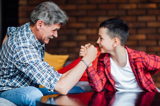 Grand-père fort jouant avec son petit-fils à la maison.