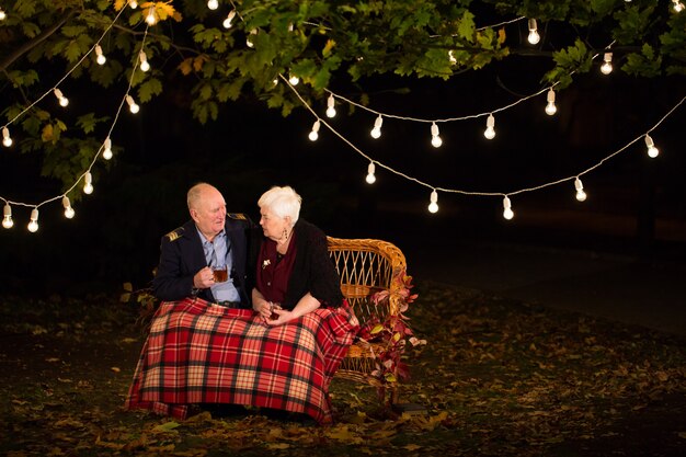 Grand-père et grand-mère boivent du thé dans le parc.