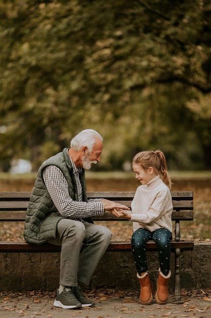 Grand-père jouant au jeu de claquement des mains rouges avec sa petite-fille dans le parc le jour de l'automne