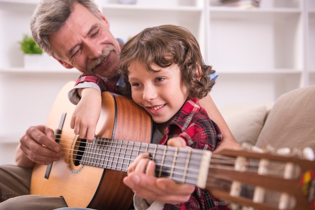 Grand-père joue de la guitare avec son petit-fils.