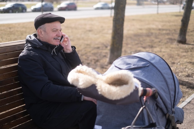 Grand-père marchant avec une poussette de bébé le jour neigeux d'hiver