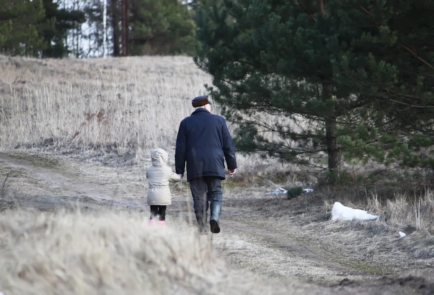 Grand-père marchant avec sa petite-fille à l'extérieur au début du printemps