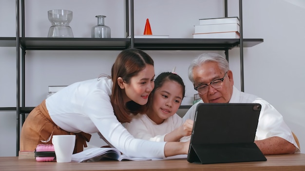 Grand-père et mère enseignent les devoirs à leur fille tout en étudiant en ligne à la maison.