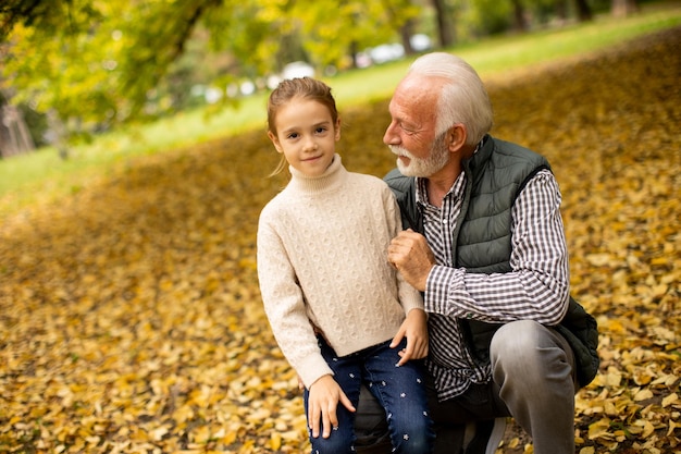 Grand-père passe du temps avec sa petite-fille dans le parc le jour de l'automne